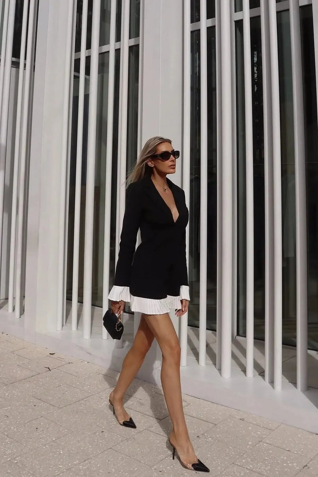 Chic women's black mini dress, featuring a flattering V-neck, tailored pleats, and stylish button front details.