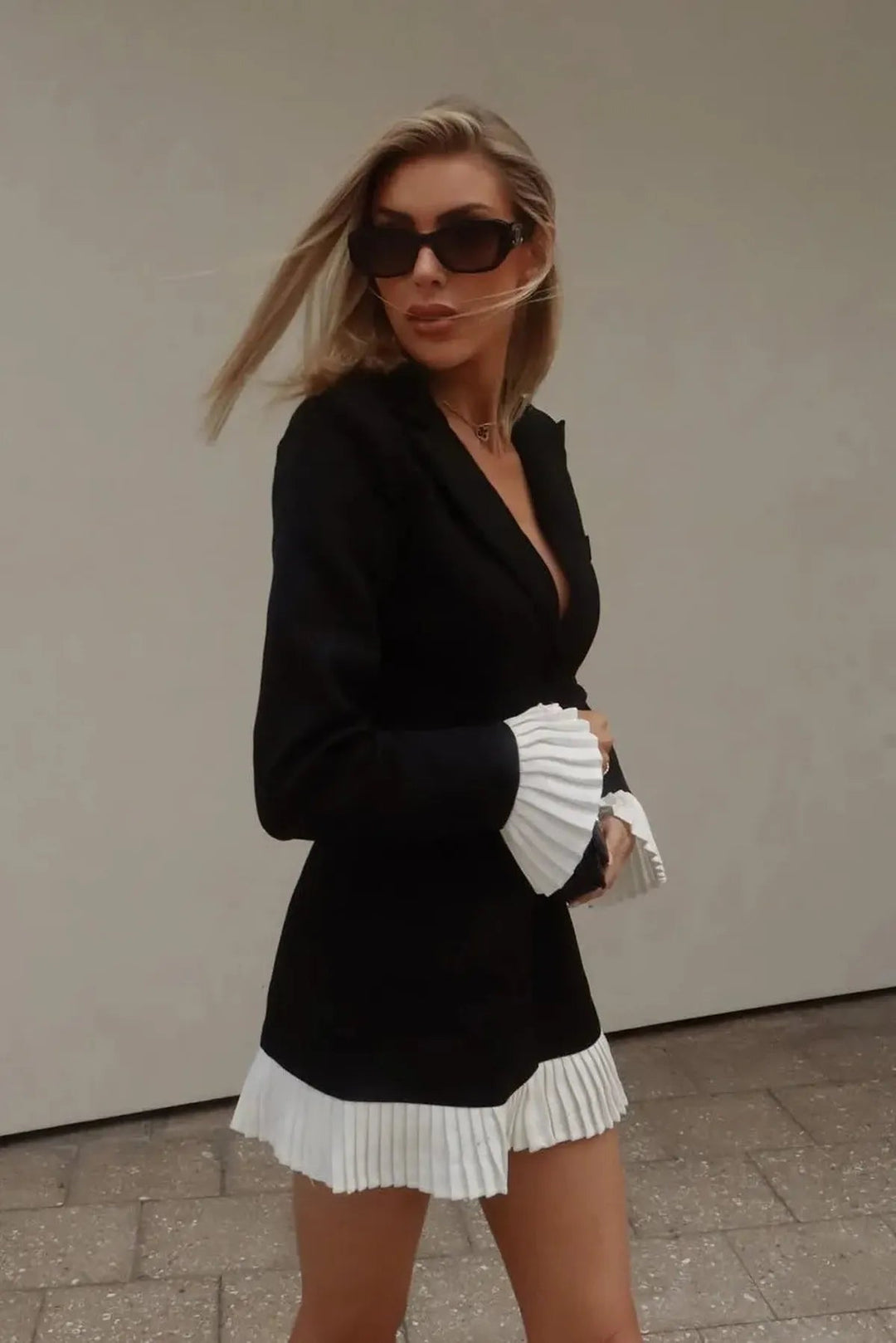 Sophisticated women's pleated mini dress in black, with a chic V-neck design and classic button front.