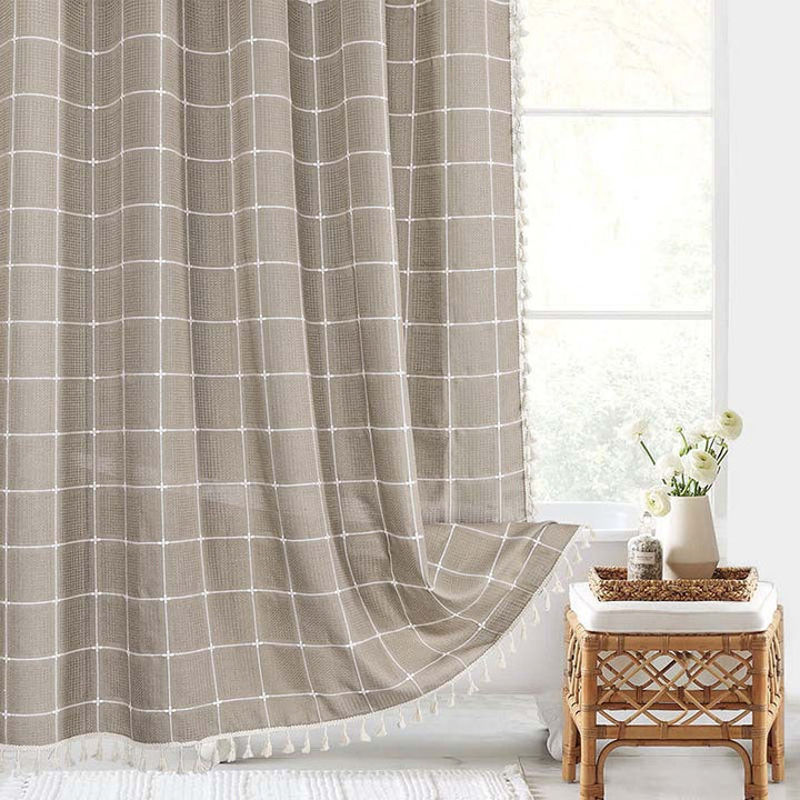 "Bohemian farmhouse waterproof linen shower curtain with decorative tassels, shown in a warm beige plaid pattern."