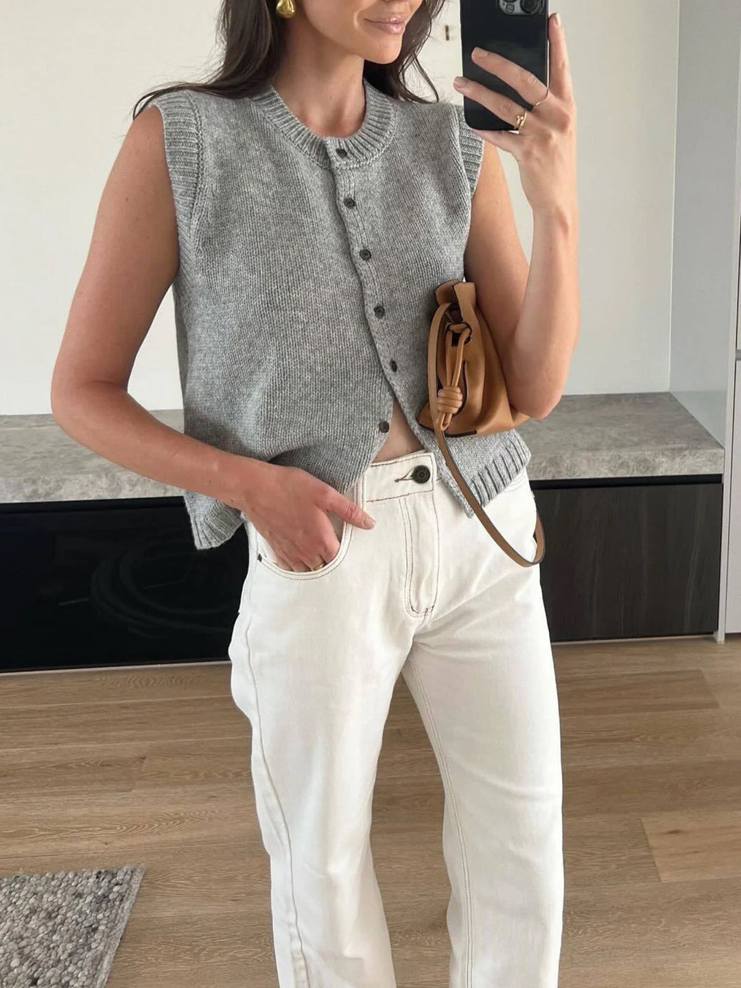 Chic women's button-up sweater vest, a sleeveless knit top in light grey, perfect for layering outfits.