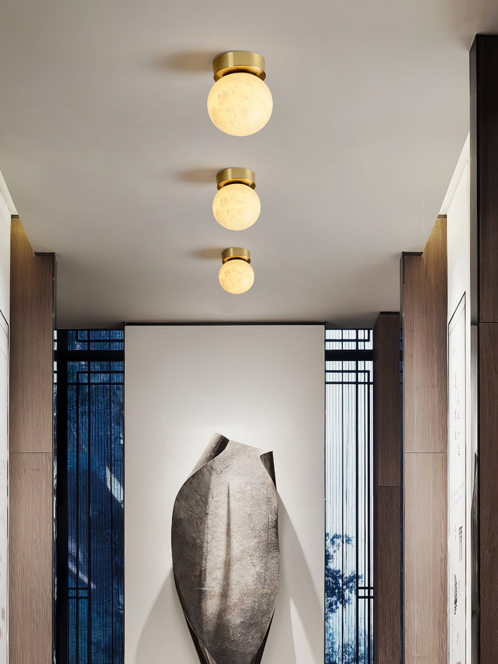Elegant alabaster brass ceiling lamp, warm ambient light, celestial glow, sophisticated brass detailing, modern design.