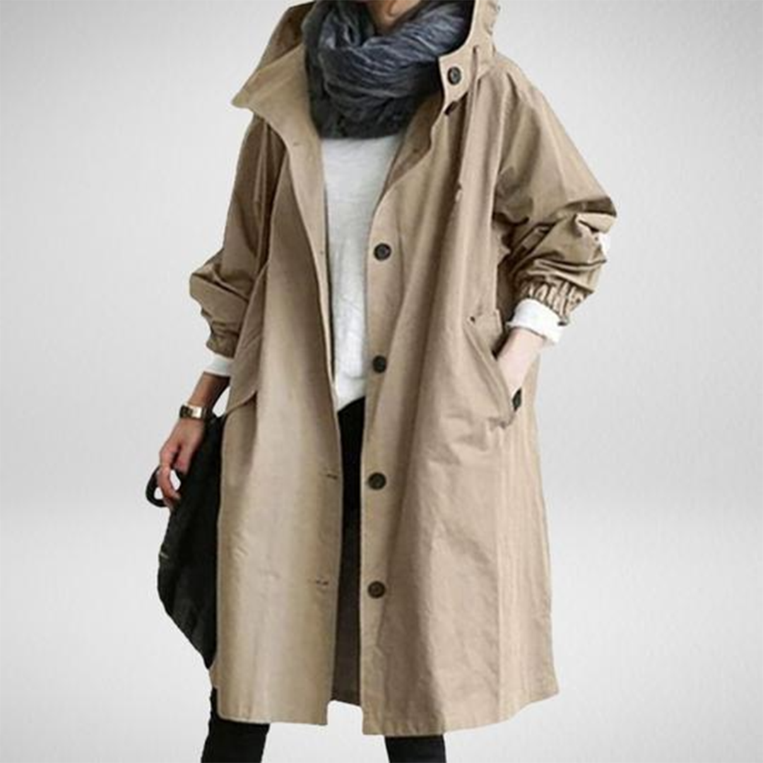 Elegant beige long waterproof raincoat for women with adjustable hood and pockets, provides style and protection in rain.