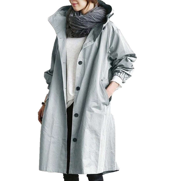 Elegant beige long waterproof raincoat for women with adjustable hood and pockets, provides style and protection in rain.
