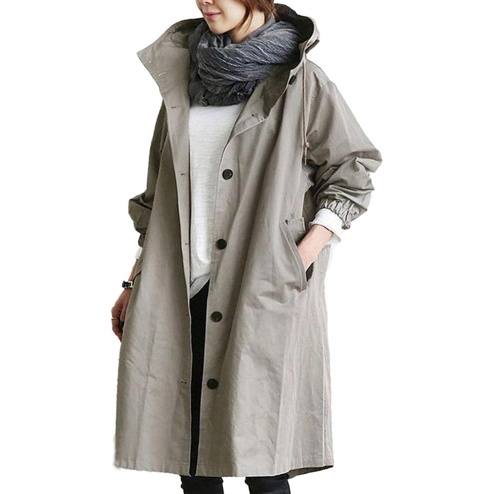 Elegant beige long waterproof raincoat for women with adjustable hood and pockets, provides style and protection in rain.