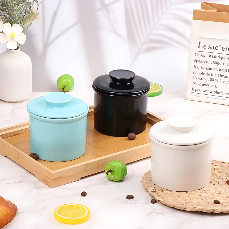 "Elegant ceramic butter keeper with water-sealed system in sleek black, light blue, and white, perfect for kitchen décor."