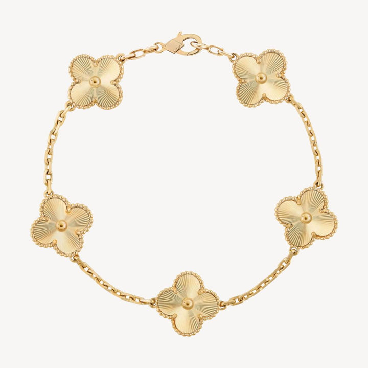 Elegant clover charm bracelet with polished black agate inlays and a gold and silver-tone chain for sophisticated style.