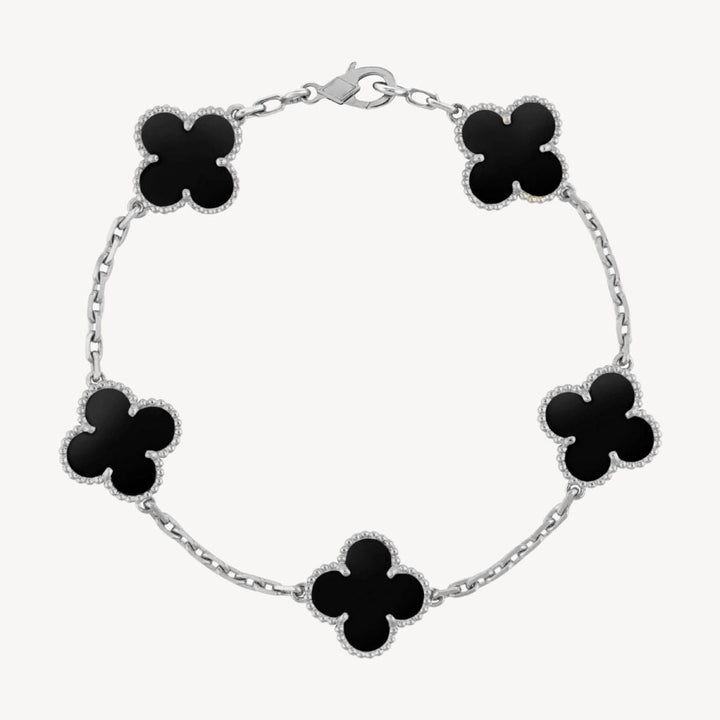 Elegant clover charm bracelet with polished black agate inlays and a gold and silver-tone chain for sophisticated style.