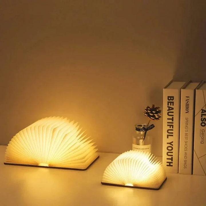 "Elegant foldable LED book lamp, warm white light, 360-degree design, portable for home or travel, wood and paper material."