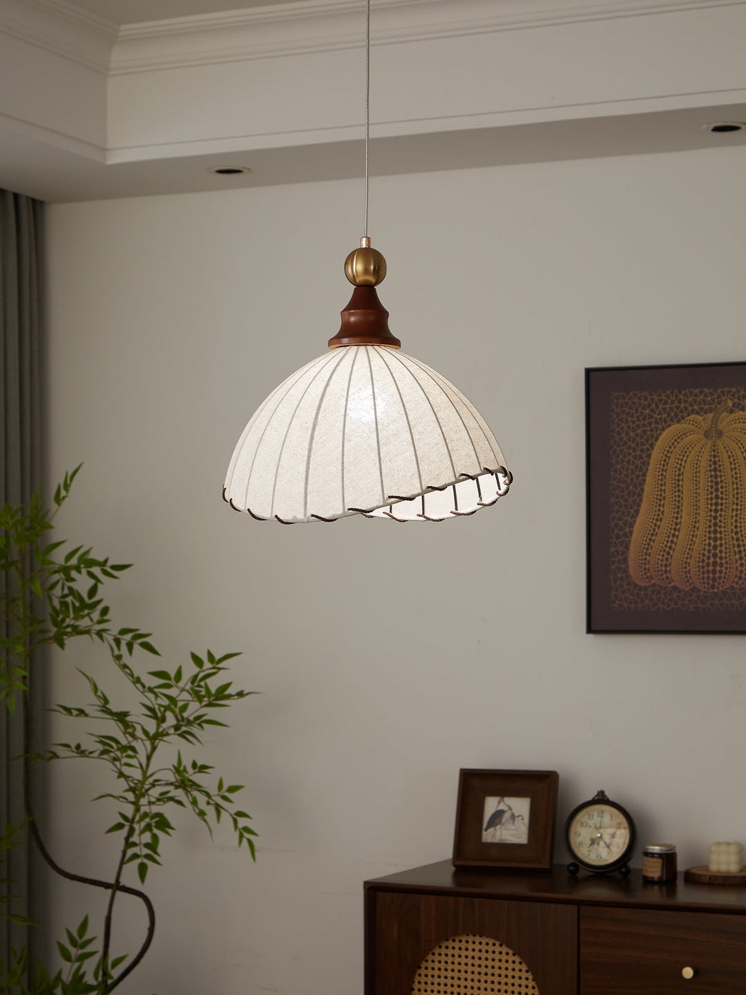 Elegant pendant light with pleated fabric shade, gold-finished top, and wood accent; perfect for modern interiors.