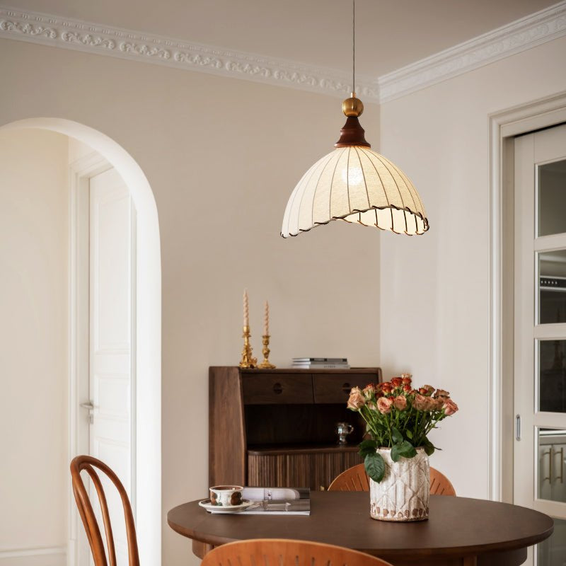 Elegant pendant light with pleated fabric shade, gold-finished top, and wood accent; perfect for modern interiors.