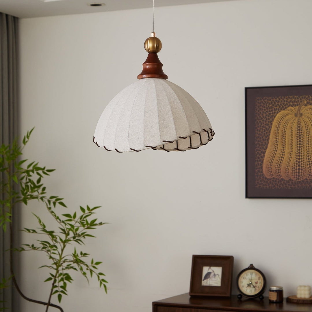 Elegant pendant light with pleated fabric shade, gold-finished top, and wood accent; perfect for modern interiors.