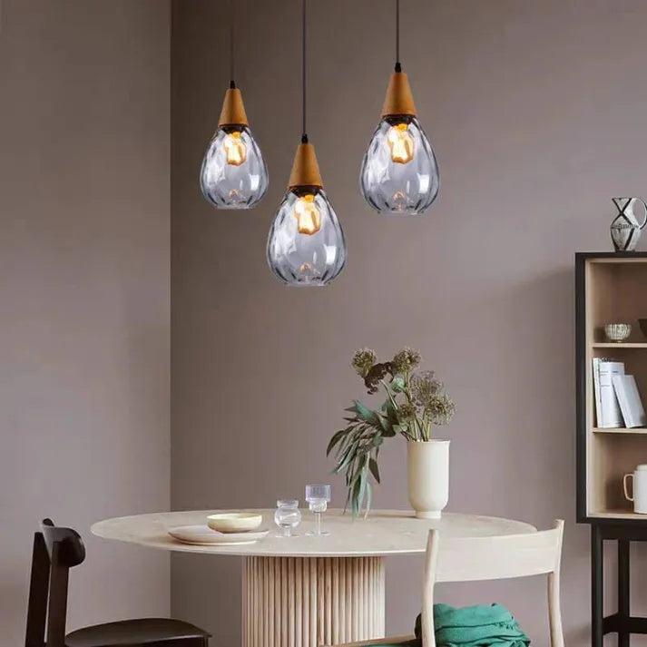 "Elegant teardrop glass pendant light with wood accents, available in clear, golden, smoky gray, perfect for any home decor."