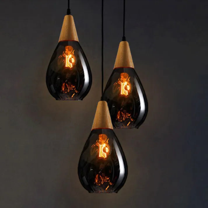 "Elegant teardrop glass pendant light with wood accents, available in clear, golden, smoky gray, perfect for any home decor."
