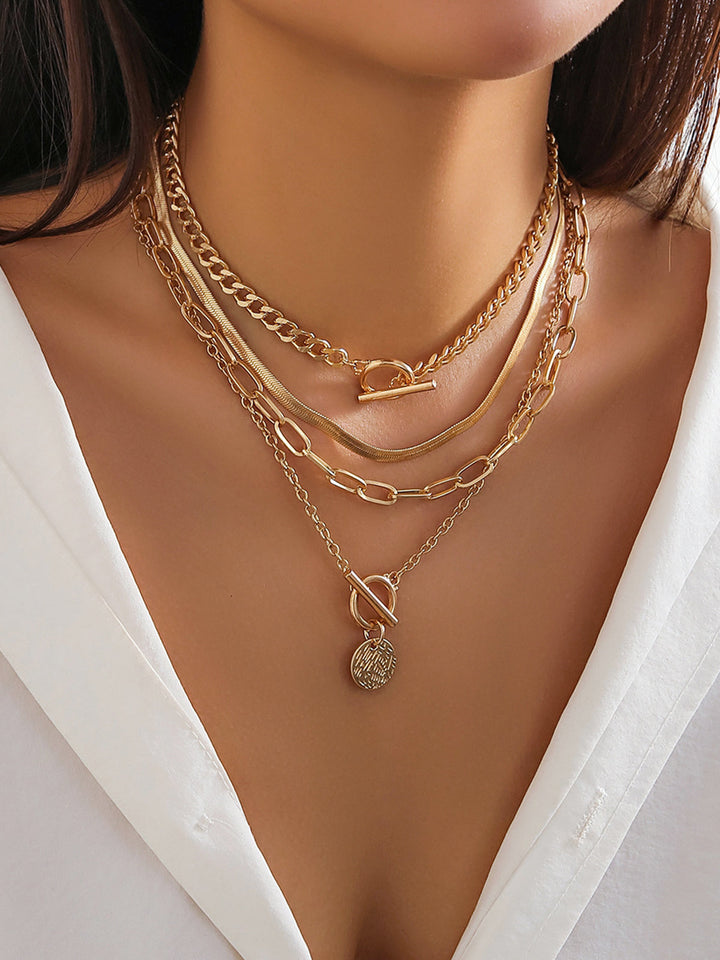 Women's gold layered necklace set featuring multiple chains & a distinctive coin pendant. Trendy jewelry.