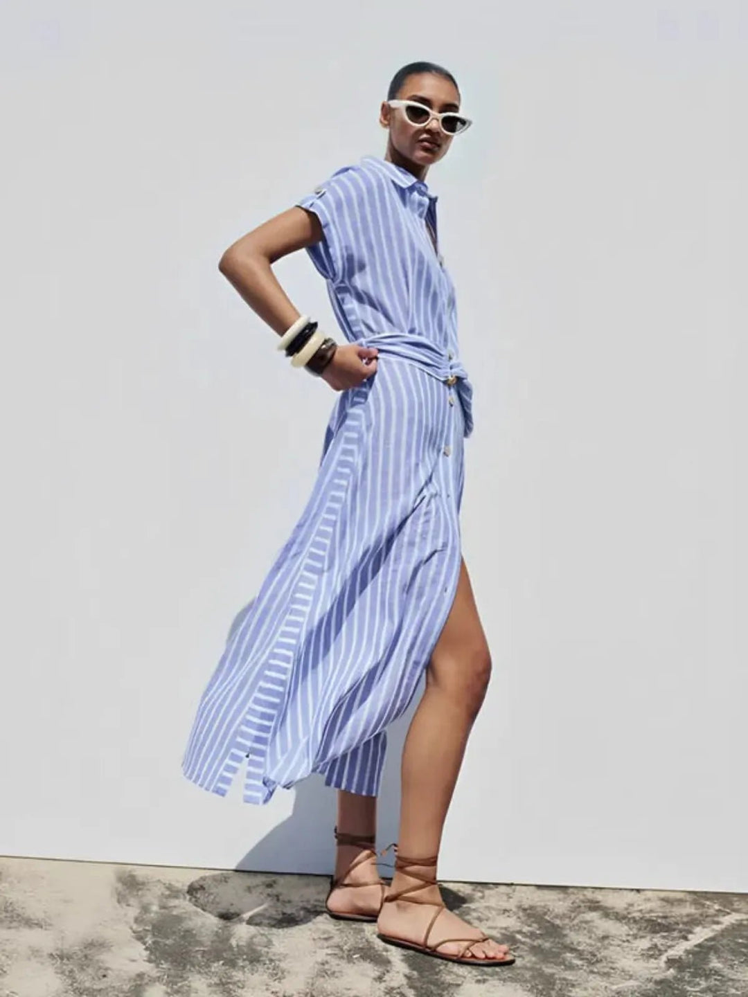 Full view of a model wearing a light blue striped belted button-down maxi dress for women.
