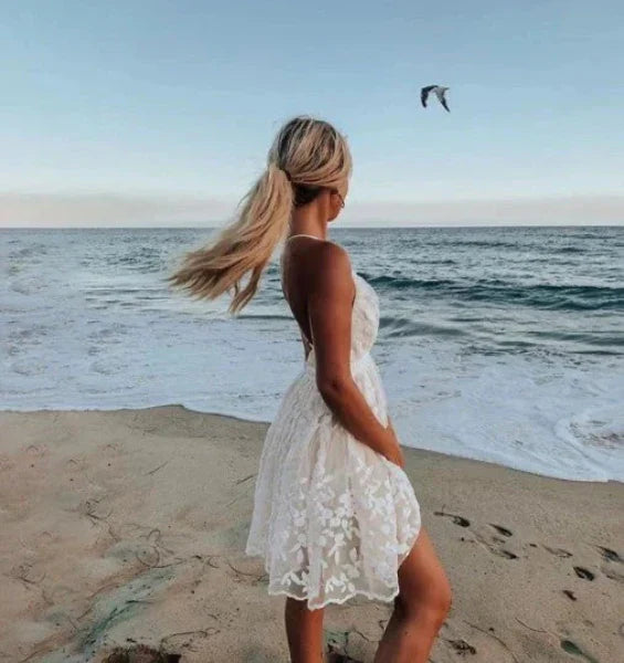 Women's white halter mini cocktail dress featuring delicate floral embroidery, ideal for summer beach parties.
