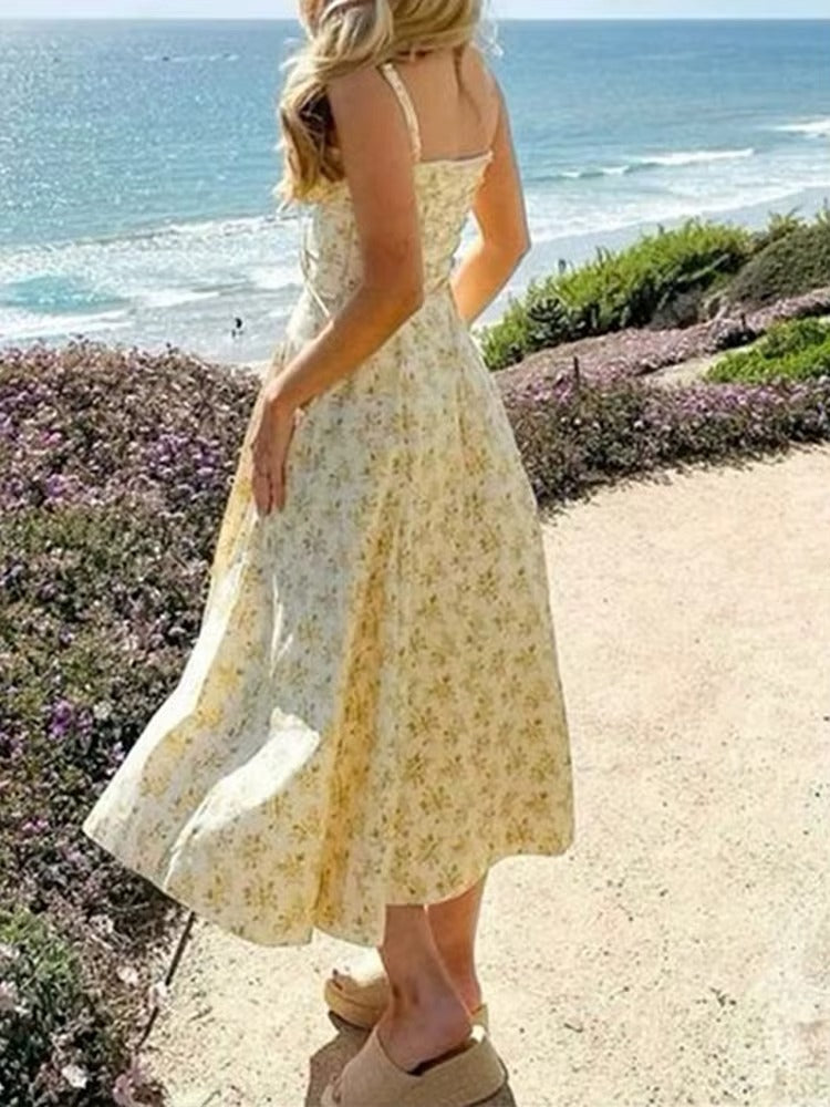 Fashionable woman modeling a flowy yellow floral summer midi dress, ideal for elegant casual occasions.