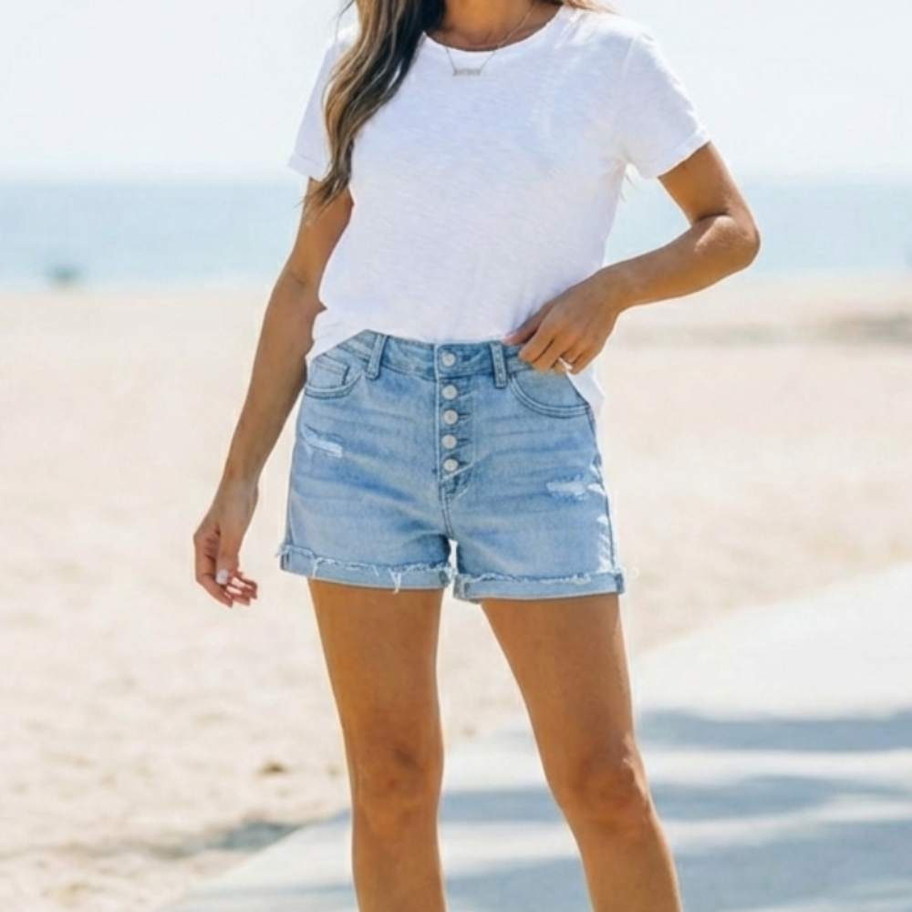 Close-up of light blue denim jorts featuring a stylish button fly. Comfortable women's mid-thigh shorts for warm weather.