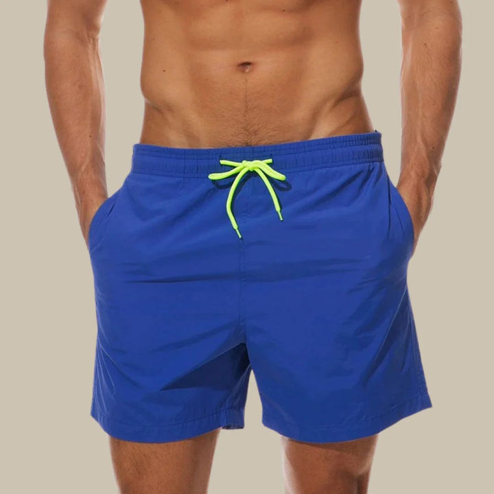 Versatile men's swim shorts with adjustable drawstring waist & practical pockets, perfect for summer comfort & beach style.