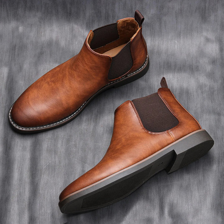 Side view of men's sleek black Chelsea boots, emphasizing elastic side panels and slip-on design.