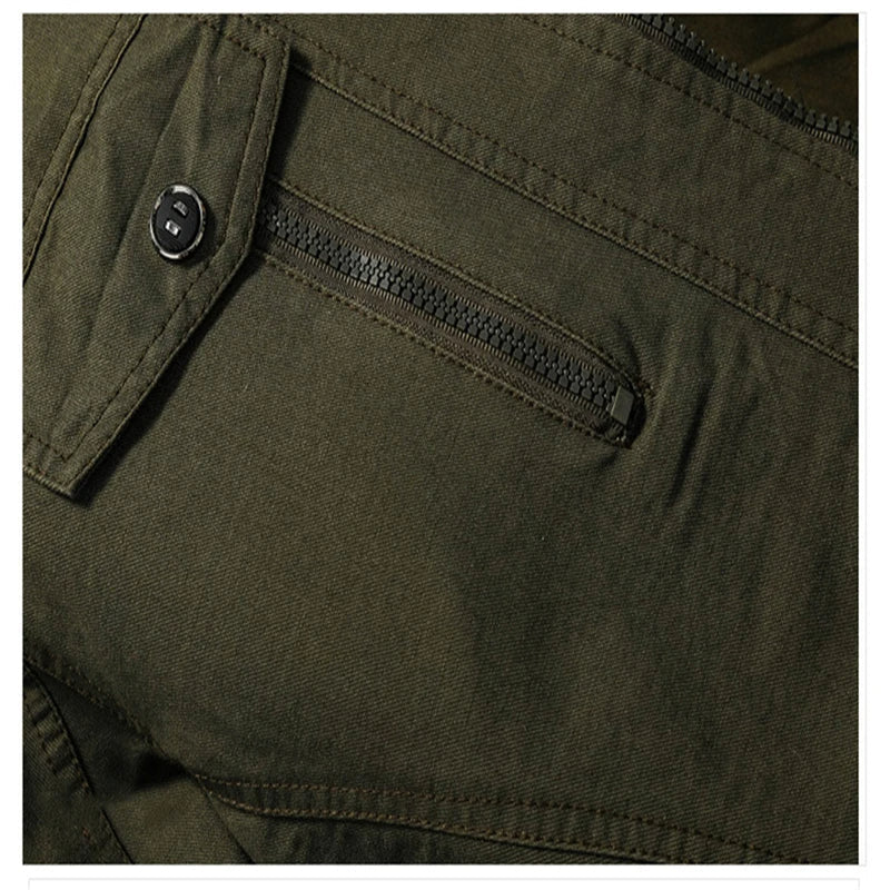 Close-up of men's military jacket showing zipper closure & chest pockets. Rugged fall/spring utility style.