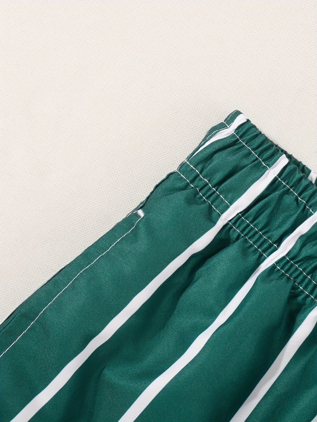 Close-up of quick-dry fabric texture & adjustable drawstring on men's striped swim shorts.