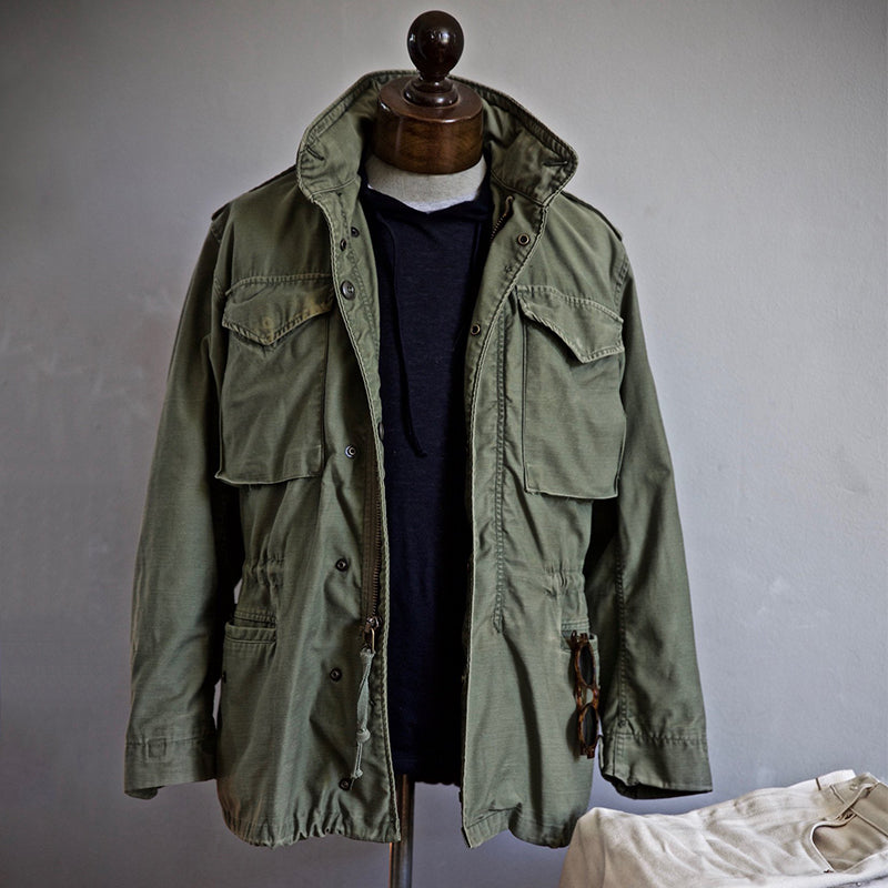 "Men's vintage military jacket with hidden hood, snap-button cargo pockets, wind-resistant, rugged style."
