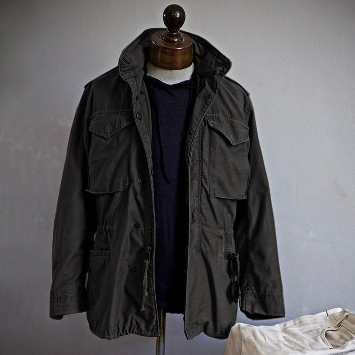 "Men's vintage military jacket with hidden hood, snap-button cargo pockets, wind-resistant, rugged style."