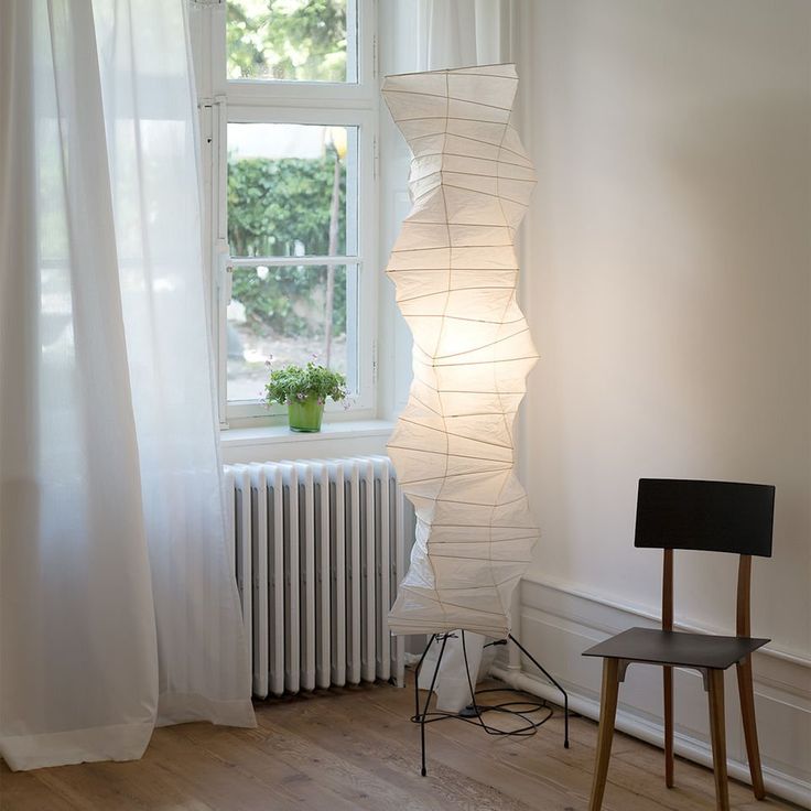 "Minimalist rice paper floor lamp with sleek metal frame and soft diffused light, perfect for creating a warm ambiance."