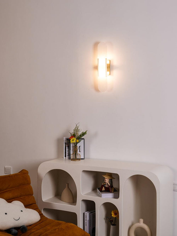 "Modern elongated alabaster wall lamp with metal and brass accents, emits warm glow, suitable for chic interior decor."