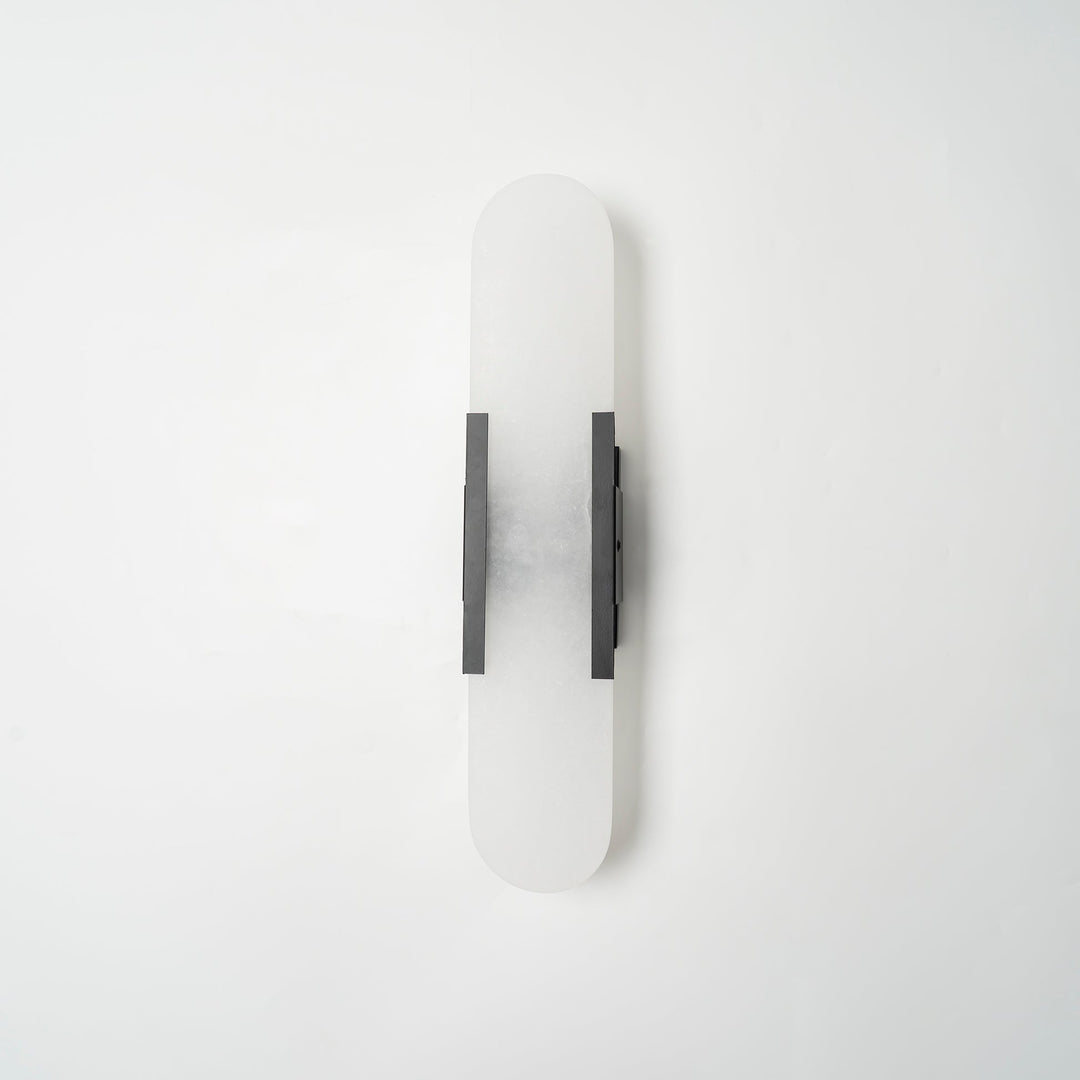 "Modern elongated alabaster wall lamp with metal and brass accents, emits warm glow, suitable for chic interior decor."