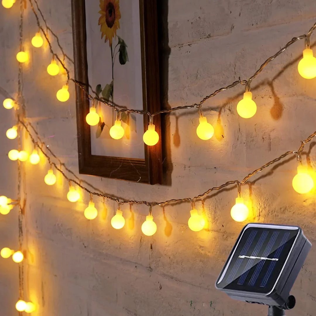 Warm white solar LED festoon lights illuminating an outdoor patio at night, creating a festive atmosphere.