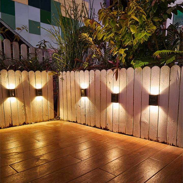 Outdoor waterproof solar wall light with motion sensor, black finish, mounted on a stone wall, illuminating a garden path.