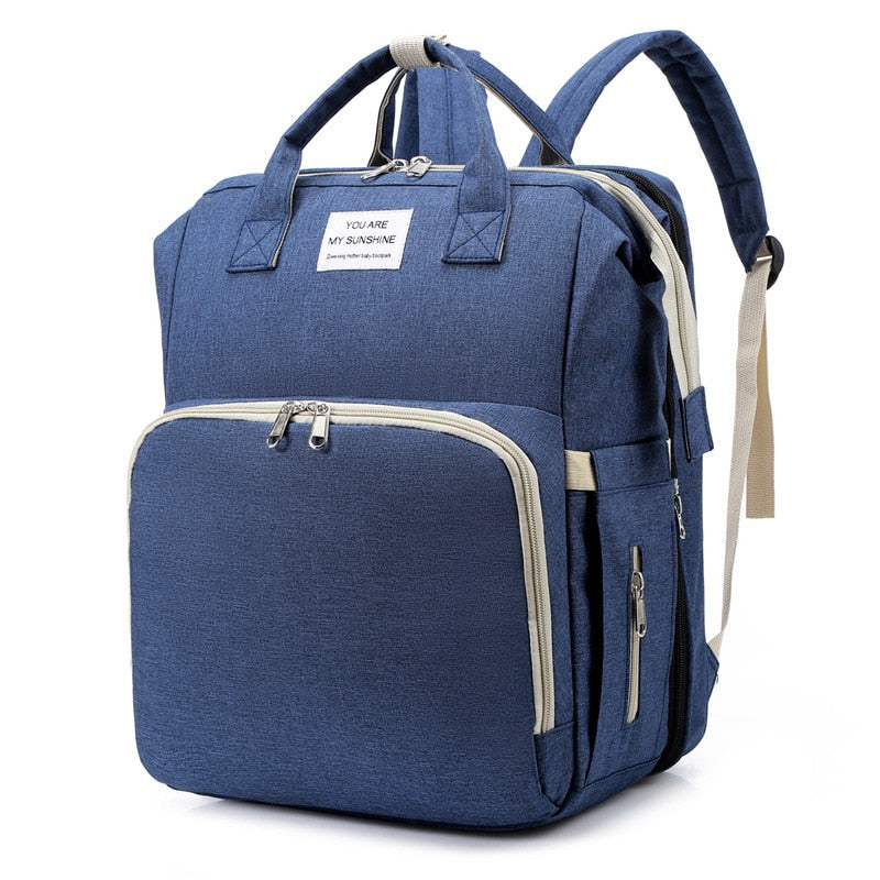 Compact diaper bag converts to a secure infant sleeping space and changing station.