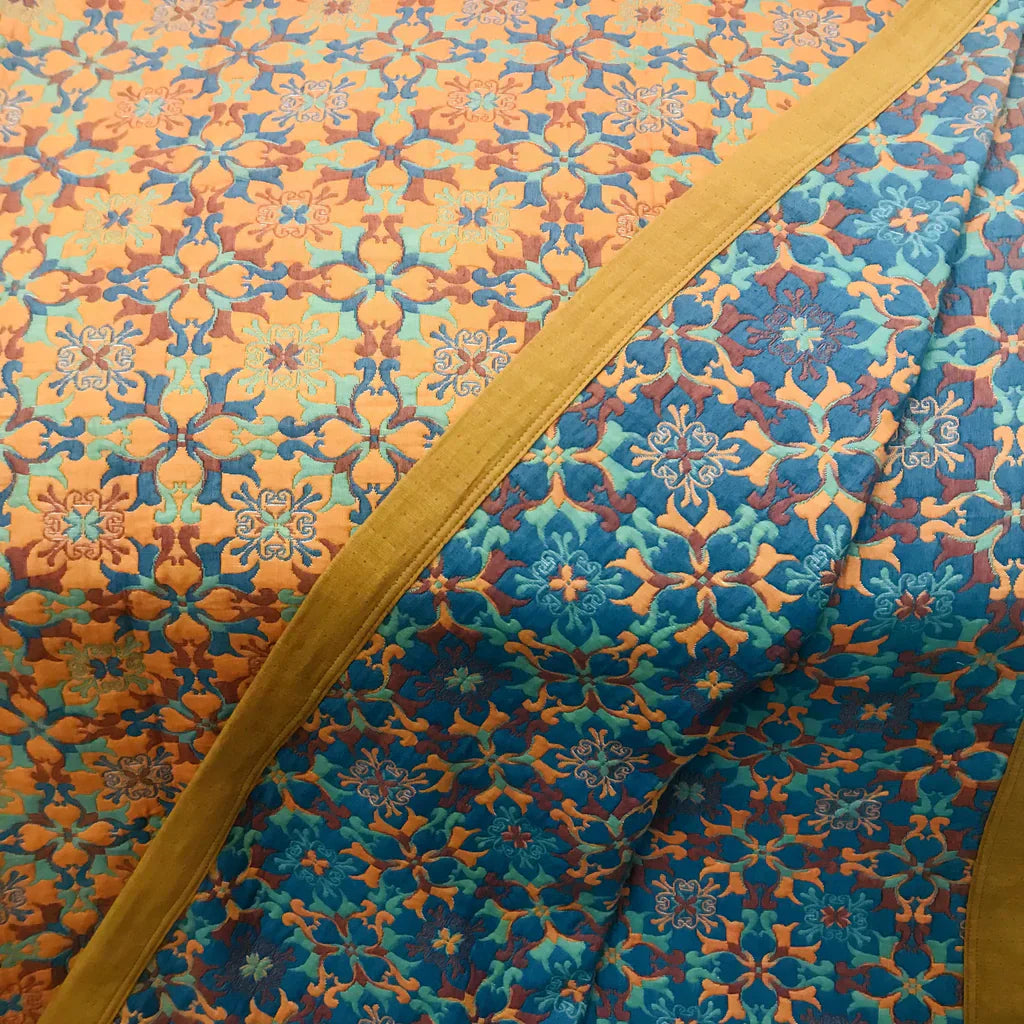 Vibrant orange & blue pattern on a six-layer cotton quilt, enhancing any cozy bedroom decor.