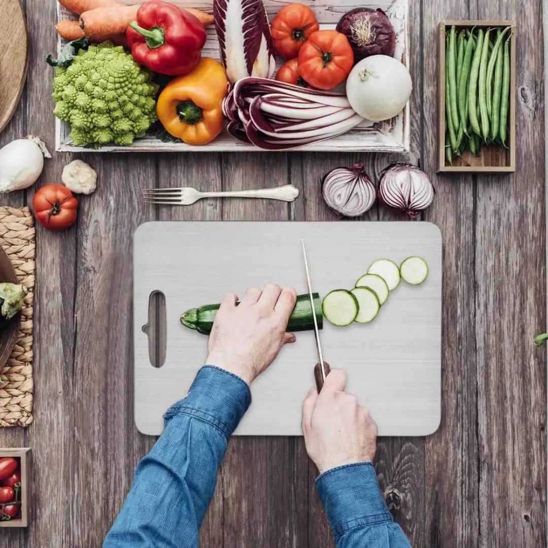 "Sleek stainless steel cutting board in use, showing durability and knife-friendly surface for kitchen prep tasks."