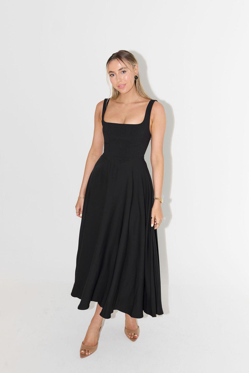 "Sleeveless satin midi dress with square neckline, fitted bodice; elegant women's fashion for special occasions."