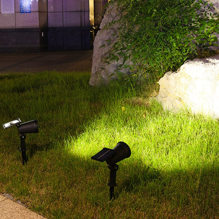 "Solar-powered LED garden spotlight with 9 color options, illuminating a pathway; eco-friendly outdoor lighting solution."