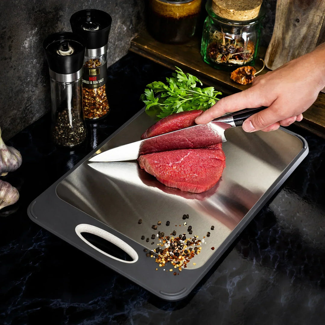 Stainless steel cutting board with a smooth finish and non-slip ergonomic handle, ideal for precise and hygienic kitchen prep