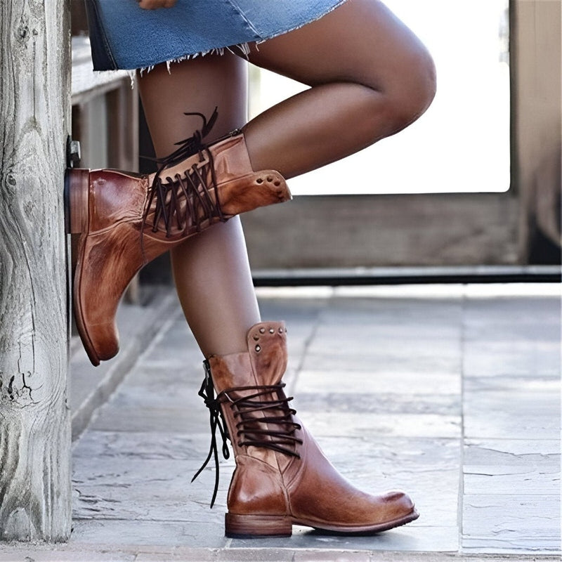 Close-up of women's black studded mid-calf boots with lace-up front and comfortable low heel.