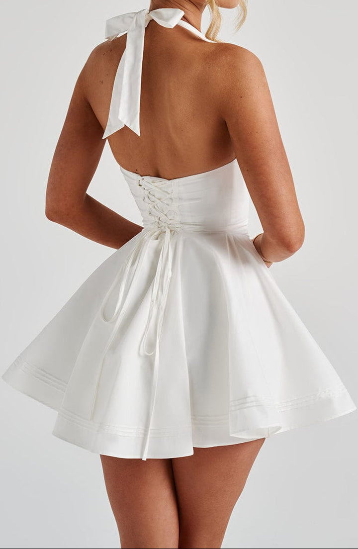 Sleeveless white halter neck mini dress with flared skirt. Ideal summer cocktail party attire.