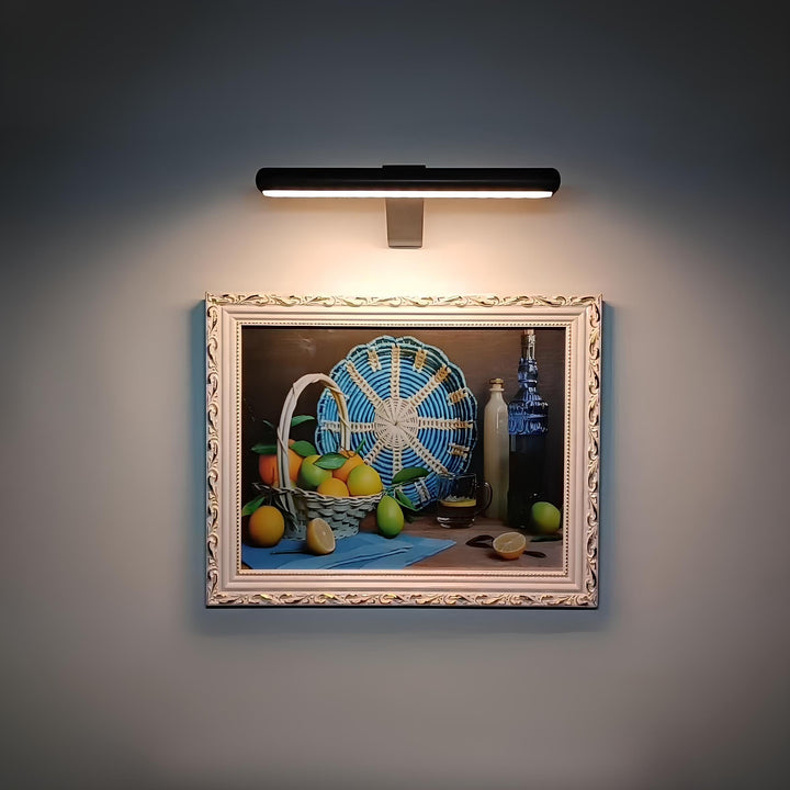 Dimmable wireless LED spotlight illuminating wall art. Rechargeable, perfect for modern home decor.