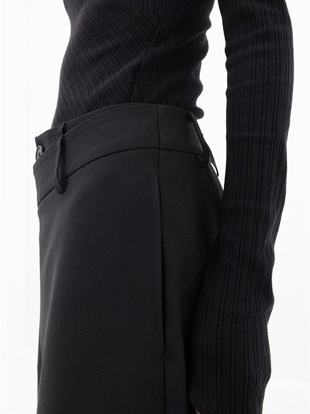 Full-length view of women's asymmetrical relaxed fit trousers, showcasing modern draped design.