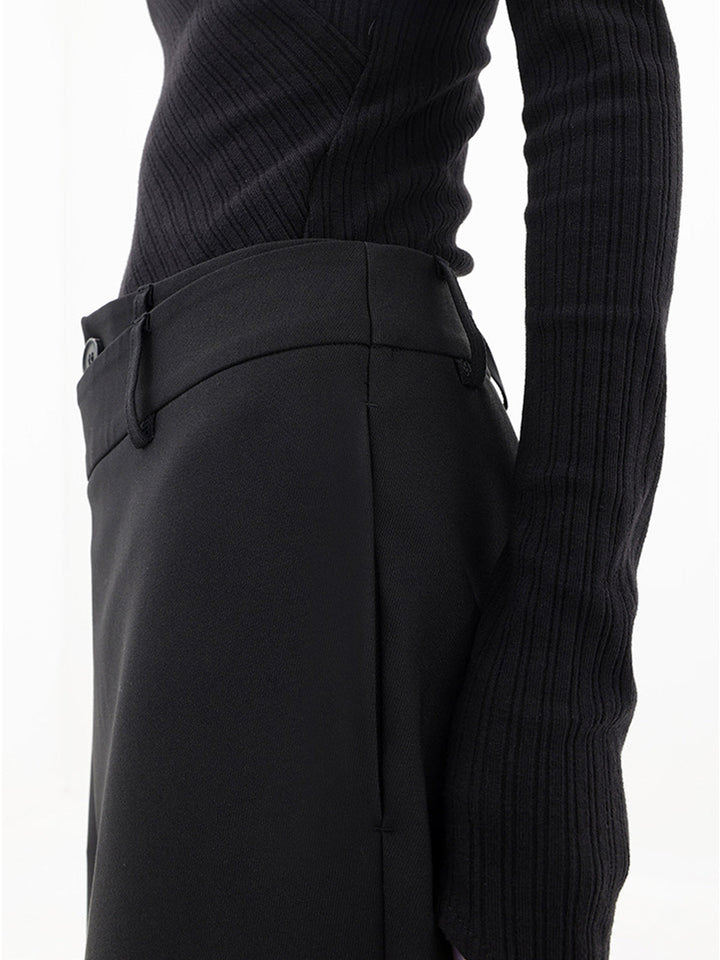 Full-length view of women's asymmetrical relaxed fit trousers, showcasing modern draped design.