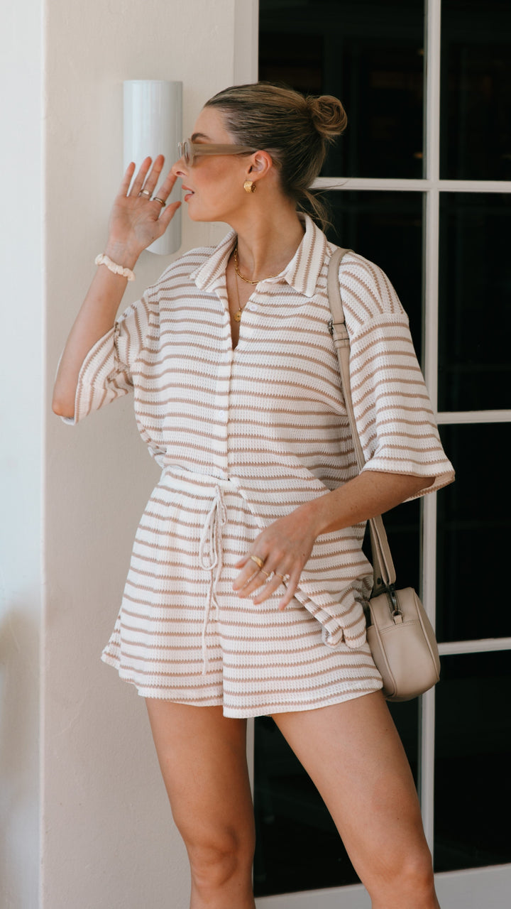 Stylish women's beige and white striped button-up shirt, part of a chic summer shorts set. Vacation wear.