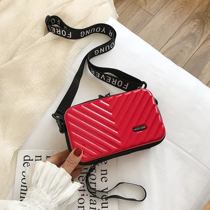 Front view of women's compact hard shell crossbody bag, sleek design, durable for travel.