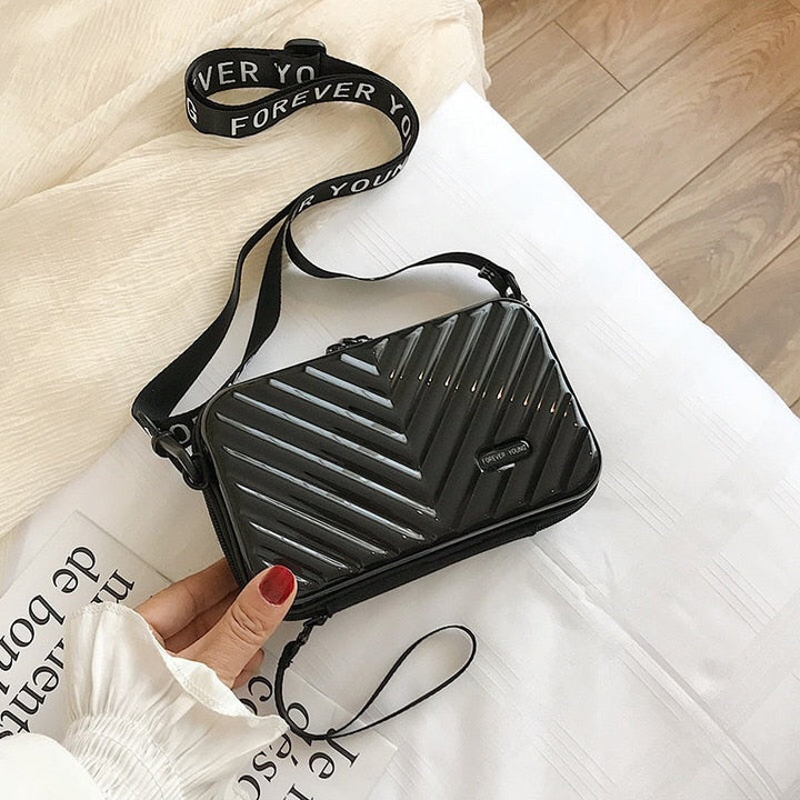Open compact hard shell crossbody bag showing organized interior, perfect for travel essentials.