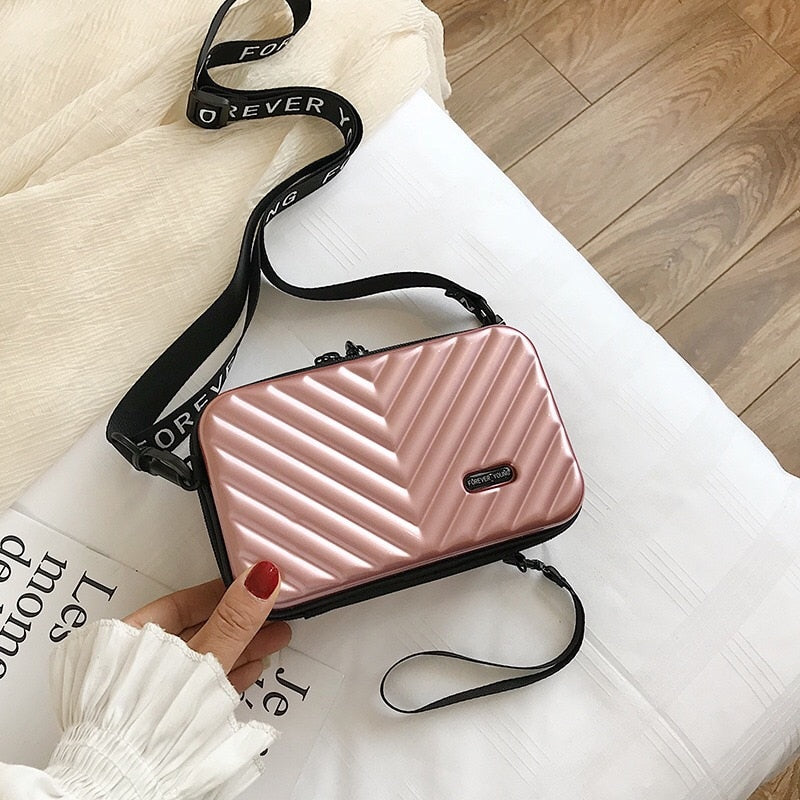Woman wearing stylish compact hard shell crossbody bag, perfect for everyday or travel.