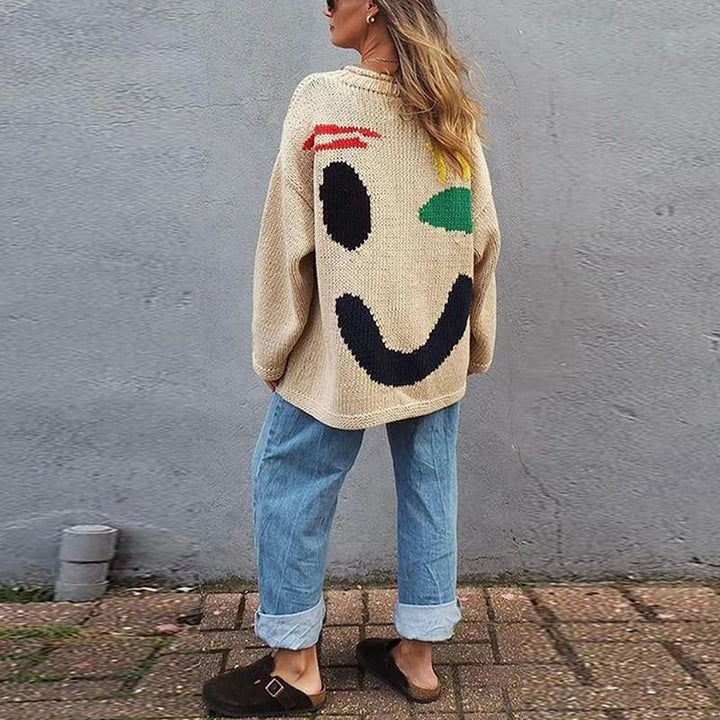 Close-up of the cheerful smiley face on a women's cozy oversized knit sweater. A trendy detail for casual wear.