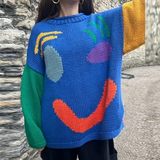 Folded women's cozy oversized smiley face sweater. Soft knit for winter warmth, loose fit, and trendy casual wear.